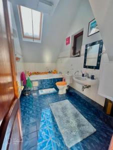 La salle de bains est pourvue de carrelage bleu, de toilettes et d'un lavabo. dans l'établissement Blue Sky, à Buşteni