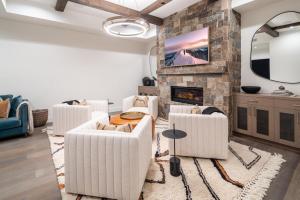a living room with white furniture and a stone fireplace at Inspiration Point Townhome 8C in Big Sky