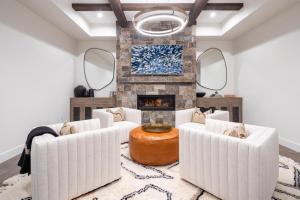 a living room with two white chairs and a fireplace at Inspiration Point Townhome 8C in Big Sky