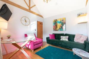 a living room with a green couch and pink chair at Grindle Cottage in Woodbury