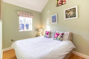 - une chambre avec un lit doté de draps et d'oreillers blancs dans l'établissement Grindle Cottage, à Woodbury