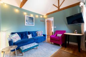 a living room with a blue couch and a pink chair at Woodbury Cottage in Woodbury