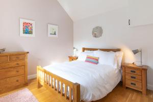 a bedroom with a large white bed and a wooden dresser at Woodbury Cottage in Woodbury