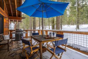 stół i krzesła na werandzie z niebieskim parasolem w obiekcie North Shore - Sierra Sky Haven w mieście Tahoe City