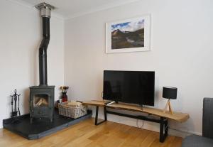 ein Wohnzimmer mit einem TV und einem Kamin in der Unterkunft Sugarloaf in Fort William