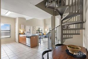 a kitchen and living room with a spiral staircase at Perfect Location Near UT and Large Patio With A View in Austin