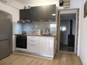 a kitchen with white cabinets and black appliances at Holiday home Marija in Vrlika