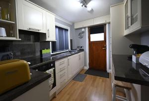 een keuken met witte kasten en een zwart aanrechtblad bij Sealladh Mairi in Fort William +13 foto's