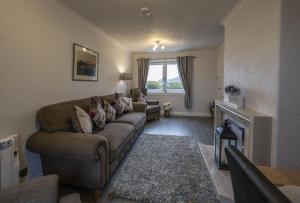 een woonkamer met een bank en een open haard bij Sealladh Mairi in Fort William