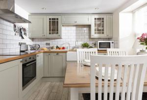 a kitchen with white cabinets and a wooden table at Oriel Cottage in St. Agnes