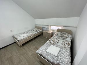 um pequeno quarto com 2 camas e uma janela em Bishkek Backpackers em Bishkek