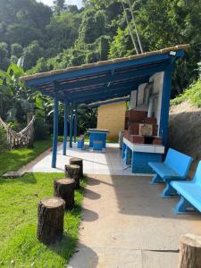 a picnic shelter with blue benches and tree stumps at Chalé Canto da Viola in São Roque