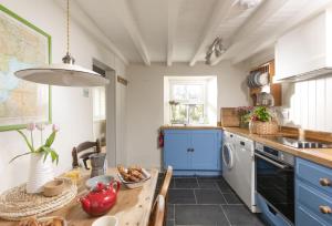 a kitchen with blue cabinets and a wooden table at Pink Cottage in Penzance