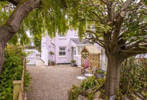 a garden with a white house and a tree at Pink Cottage in Penzance
