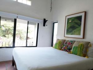 a bedroom with a large white bed and windows at Estudio sobre calle principal con vista a la plaza in Sayulita