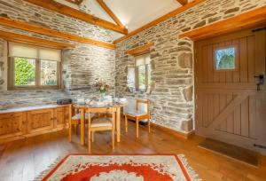 a dining room with a table and a stone wall at The Threshing Barn in Gwennap