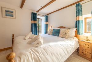 a bedroom with a white bed with blue curtains at The Threshing Barn in Gwennap