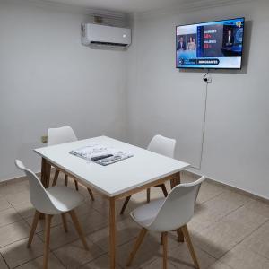 mesa blanca con sillas y TV en la pared en Departamento av.Cordoba en San Juan