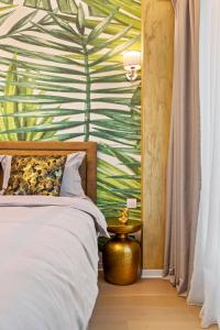 um quarto com uma cama com papel de parede de folha tropical em ONE Tower Apartments em Bucareste