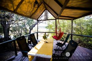 einen Tisch und Stühle auf einer Veranda mit Schaukel in der Unterkunft Kubu & Kwena Lodge in Katima Mulilo