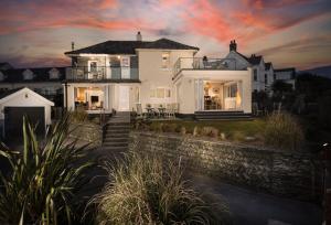 a large white house with a sunset in the background at Trewalder in St Merryn