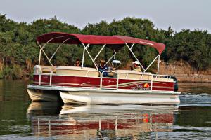 a boat with a red roof on the water at Kubu & Kwena Lodge in Katima Mulilo