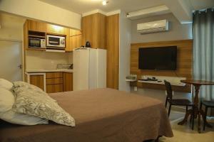 a bedroom with a bed and a kitchen with a refrigerator at Para casais, prédio beira mar, em frente à Roda Gigante in Balneário Camboriú