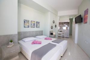 a bedroom with a large white bed with pink pillows at Sea Side Rooms in Rhodes Town