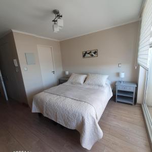 1 dormitorio con 1 cama con colcha blanca en Departamento Centro Osorno en Osorno