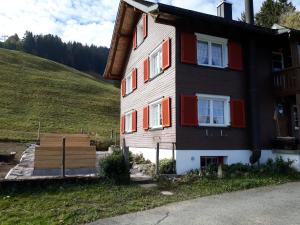 una casa con persianas rojas en una colina en Bauernhaus Cafrida, en Flumserberg