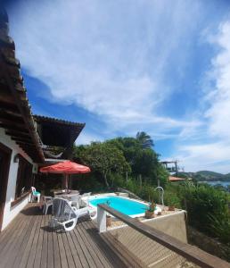 um deque com uma piscina e um guarda-sol em Casa Panorâmica da Ferradura em Búzios