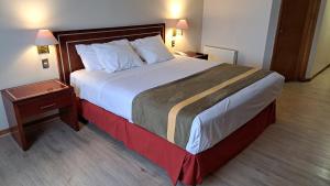 a hotel room with a large bed and a night stand at Hotel Diego de Almagro Puerto Montt in Puerto Montt