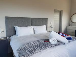 Una gran cama blanca con una manta. en Southern most tip of Africa apartment with sea views, en Agulhas