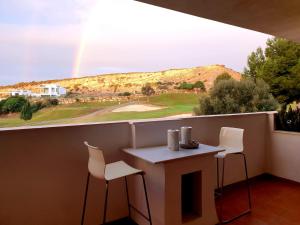 einen Tisch und Stühle auf einem Balkon mit Regenbogen in der Unterkunft Hacienda Dona JULIA GOLF Estepona in Casares
