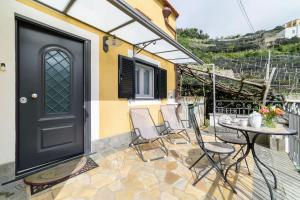 a patio with a black door and chairs and a table at #La limonaia della torretta in Minori