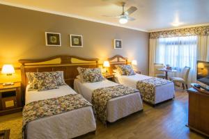 a hotel room with two beds and a television at Hotel Recanto da Serra in Gramado