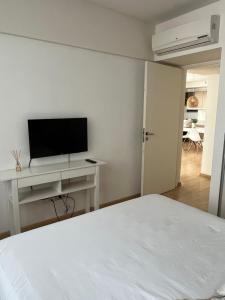 Habitación blanca con cama y TV en Departamento 2 amb de lujo en Belgrano 2B en Buenos Aires