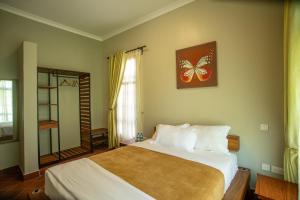1 dormitorio con 1 cama grande y espejo en Kinga Homes Boutique Hotel, en Moshi