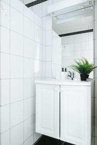 a white bathroom with a sink and a potted plant at City Center Apartment in Bergen