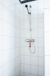 ベルゲンにあるCity Center Apartmentの白いタイルの壁にシャワーヘッド付きのシャワーが備わります。