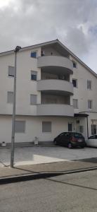 a building with a car parked in a parking lot at Apartman Polaris Posušje in Posušje