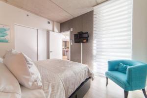 1 dormitorio con 1 cama y 1 silla azul en Les Immeubles Charlevoix - 760-416 en Quebec