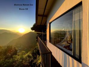 a woman looking out of a window at the sunset at Glorious Nature Inn in Ella