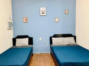 two beds in a room with blue walls at Casa Perlita, acogedora y privada. in Palenque