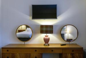 two mirrors on a table with a bed and a tv at The Bridge Helmsdale in Helmsdale