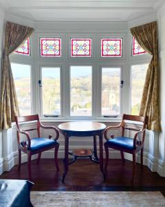 a table and two chairs in a room with windows at The Views Bed and Breakfast in Llangollen