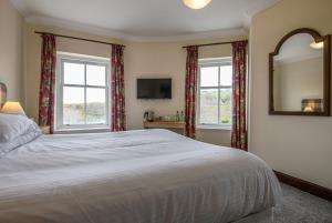a bedroom with a large bed and two windows at The Bridge Helmsdale in Helmsdale