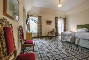 a hotel room with two beds and a chair at The Bridge Helmsdale in Helmsdale