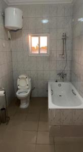 a bathroom with a toilet and a tub and a window at Coco Island in Bathurst