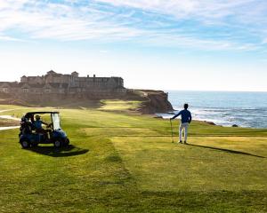 a man standing on a golf course with a golf cart at The Ritz-Carlton, Half Moon Bay in Half Moon Bay